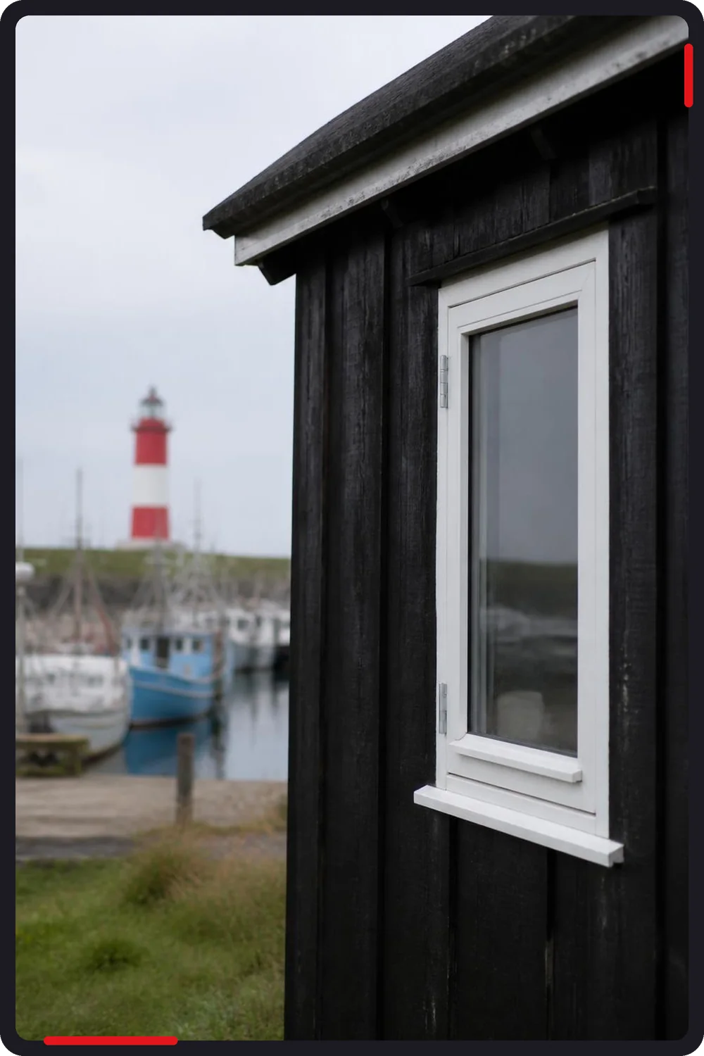 Glarmester i Gilleleje: hvidt trævindue i sort fiskerhus ved havnen
